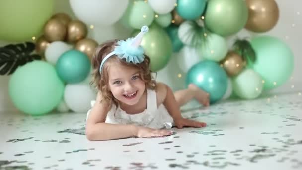 Κοριτσάκι Γιορτάζει Γενέθλιά Της Φυσώντας Κομφετί Στο Φόντο Των Μπαλονιών — Αρχείο Βίντεο