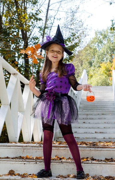 Happy girl in a witch costume on Halloween in the open air in the park