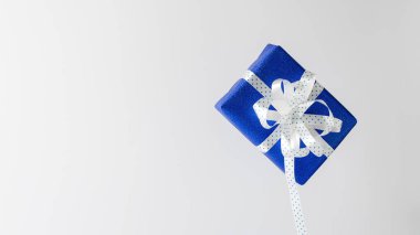 Açık arkaplanlı beyaz kurdeleli ve boş boşluklu mavi kağıtta noel hediyesi