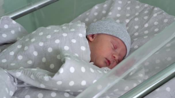 Recém-nascido bebê vermelho bonito rosto retrato primeiros dias dormindo na cama de vidro médica em fundo cinza. Criança no início minutos de vida no chapéu. Bebês, Parto, Primeiros Momentos de Borning, Princípio de Início — Vídeo de Stock