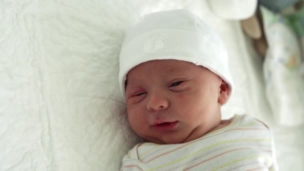 Sveglio neonato Ritratto facciale Acne Irritazioni allergiche Starnuto dei primi giorni su sfondo bianco. Bambino inizio minuti di vita sul cappello. Neonati, Parto, Primi momenti della nascita, Inizio del concetto — Video Stock