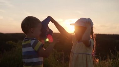 Sevimli anaokulu çocuğu ve oğlan gün batımından önce uzun otların arasında dağın tepesinde şapkalarını değiştiriyorlar. Çocuk çayırda yürüyor. Dağlarda mutlu bir çocuk. Çocukluk, doğa, yaşam tarzı, yaz konsepti