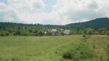 Yüksek hızlı trenin penceresinden manzarası güzel doğa manzarası vahşi tarlalar ve dağların ormanı yaz arka planında bulutlu, güneşli bir günde. Ulaşım, seyahat, demiryolu, iletişim konsepti