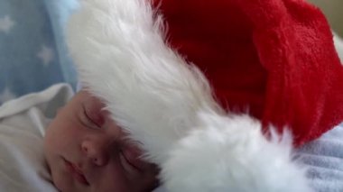 Hayatın ilk günleri yakın plan, yeni doğan tatlı, komik, Noel Baba 'nın içinde uyuyan bebek, kırmızı şapkalı, mavi yıldızlı arka planda yatıyor. Mutlu Noeller ve mutlu yıllar, bebekler, çocuklar, tatiller