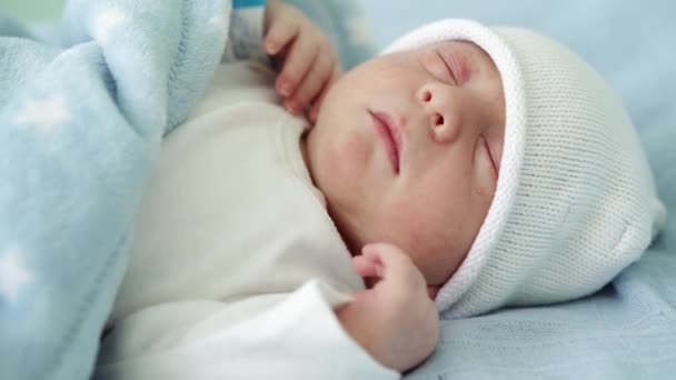 Primer plano del retrato de la cara del bebé recién nacido Primeros días durmiendo dulcemente sobre fondo azul blanco. Niño al principio Minutos de la vida en sombrero. Bebés, Parto, Primeros Momentos Del Nacimiento, Principio Concepto — Vídeos de Stock