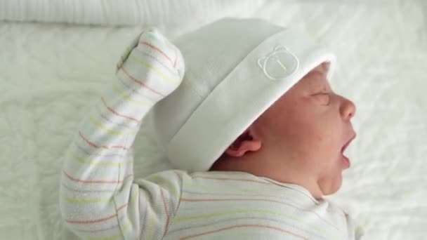 Sveglio neonato Ritratto facciale Acne Irritazioni allergiche Starnuto dei primi giorni su sfondo bianco. Bambino inizio minuti di vita sul cappello. Neonati, Parto, Primi momenti della nascita, Inizio del concetto — Video Stock