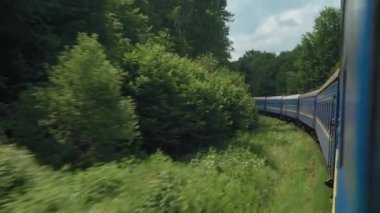 Yüksek hızlı trenin yan görüntüsü güzel doğa manzarası vahşi arazi ve dağların ormanı yaz arkaplanındaki bulutlu güneşli bir günde. Ulaşım, seyahat, demiryolu, iletişim konsepti