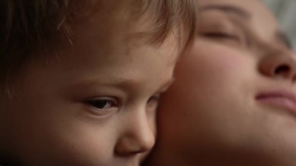 Pieni söpö unelias pieni vauva hellästi halata suudella huolehtien rentoutua syleillä hymyilevä vanhempi äiti äiti. Lapsuus, äitiys, rakkauden käsite. Lasten tunteet. Kid Focused Look. Valkoihoisen pojan muotokuva — kuvapankkivideo