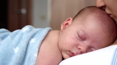 annelik, çocukluk, aile, bakım, sağlık, annelik konsepti - sıcak mavi battaniyeye sarılı yeni doğmuş bebek anne göğsünün kollarında uyuyor. Anne rahatla, kucağında öpücükle kucağında bebekle evde.