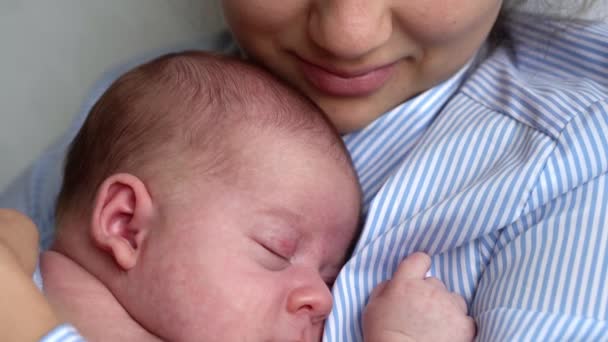 Macierzyństwo, dzieciństwo, rodzina, opieka, zdrowie, koncepcja macierzyństwa - pieczenie noworodka owiniętego w ciepły niebieski koc śpiącego na rękach matki w klatce piersiowej. Mama zrelaksować trzymając pocałunek przytulić ciążę niemowlę w domu — Wideo stockowe