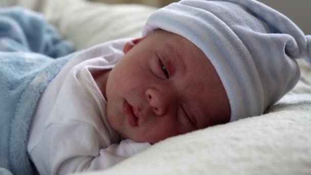 Primo piano Neonato Ritratto del viso Primi giorni Dormire dolcemente su sfondo bianco blu pancia. Bambino all'inizio Minuti di vita sul cappello. Neonati, Parto, Primi momenti della nascita, Inizio del concetto — Video Stock