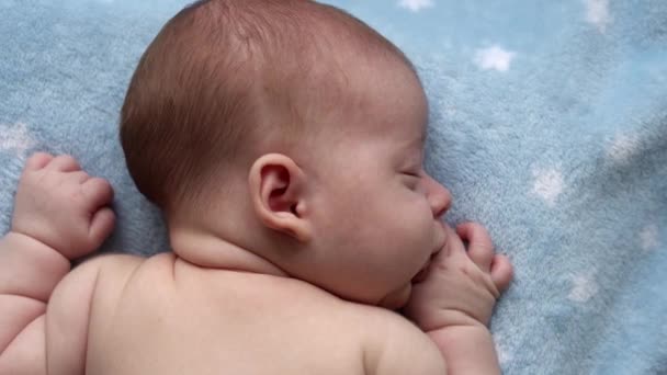 Bebeklik, çocukluk, gelişme, sağlık, aşk, bakım konsepti - yeni doğmuş çıplak yüzün üst görüntüsü evde yumuşak mavi bir kolyede karnının üzerinde uzanan küçük bebek çocuk rahatla — Stok video