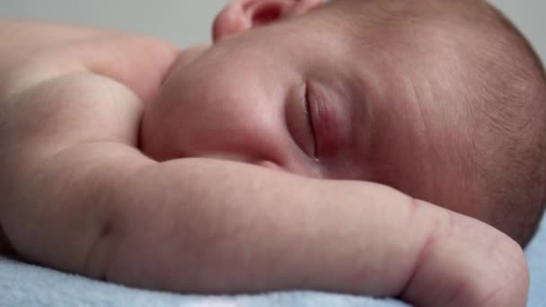 Kojence, dětství, vývoj, medicína a zdraví, láska, péče koncept - close-up tvář novorozence nahé spací malý kojenec chlapec ležící na břiše na měkké modré banket na posteli doma — Stock video
