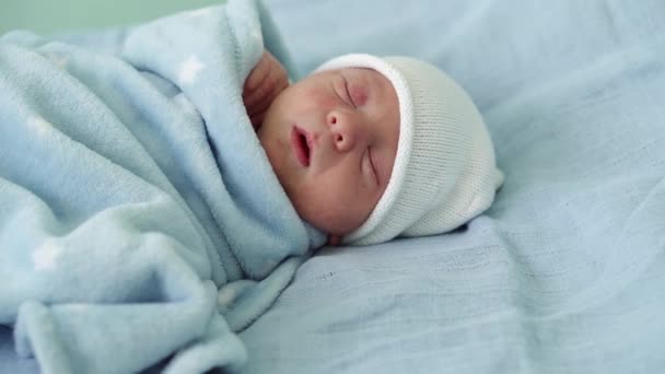 Retrato de rosto de bebê recém-nascido Irritações alérgicas da acne primeiros dias dormindo em fundo azul. Criança no início minutos de vida no chapéu. Bebês, Parto, Primeiros Momentos de Borning, Princípio de Início — Vídeo de Stock
