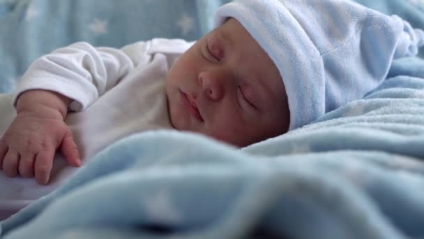 新生児の顔の肖像画のクローズアップブルースターの背景でマクロ睡眠の初期の日.帽子の上の生活の開始時に子供。幼児、出産、誕生の最初の瞬間、概念の始まり — ストック動画