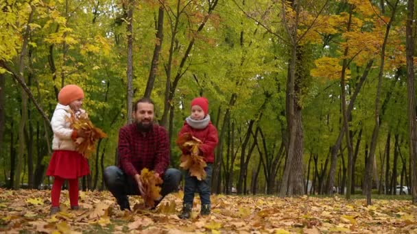 Two happy funny family daddy children kids have fun in park with dad father enjoying autumn fall nature weather. Kid Collect throw up leaves in baskets spend time together playing on forest landscape — Stock Video