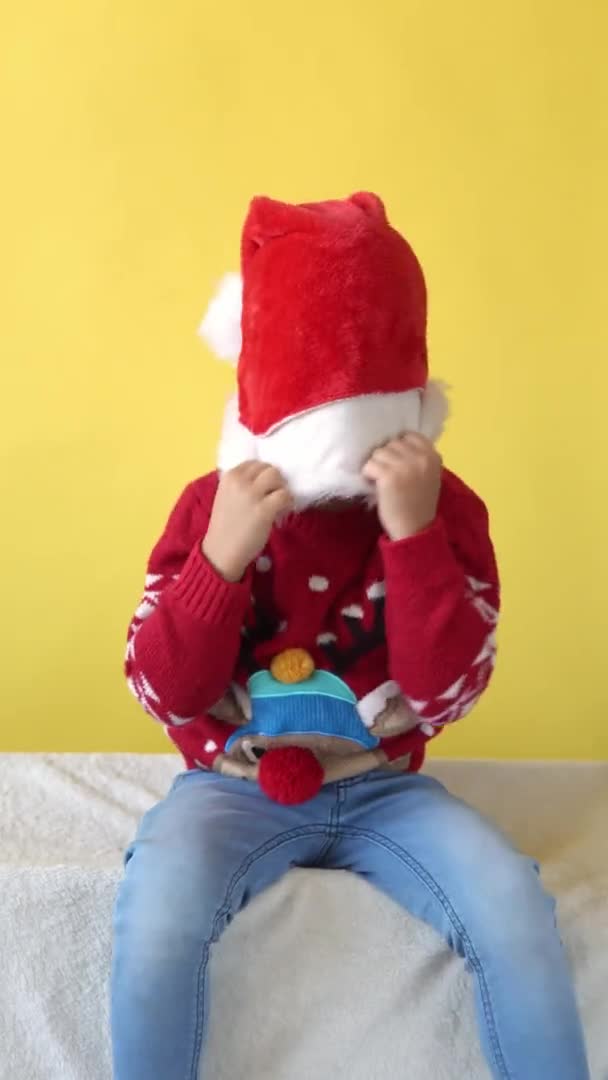 Vertical Portrait Emotion Cute Cheerful Funny Preschool Baby Boy Laughing Fooling Around In Santa Hat Looking On Camera. Yellow Background. Child Christmas Celebrate. Kid Have Fun Spend New Year Time — Stock Video