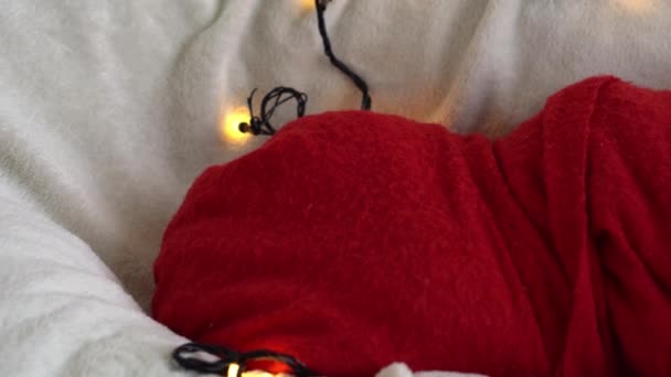 Close Up Retrato Primeiros Dias de Vida Recém-nascido Bonito Engraçado Adormecido Bebê Em Santa Chapéu Envolvido Em Fralda Vermelha Em Fundo Garland Branco. Feliz Natal, Feliz Ano Novo, Bebê, Infância, Conceito de Inverno — Vídeo de Stock