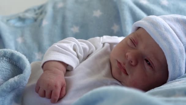 《宏观睡眠与睁开眼睛看蓝星背景》中的新生儿脸谱。孩子在生命的开始时刻在帽子上。婴儿、分娩、分娩的第一时间、开始概念 — 图库视频影像