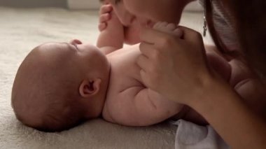 Otantik yakın çekim genç neo anne, doğum gününde beyaz yumuşak bir yatakta yeni doğmuş bebek bebekle oynuyor. Çocuk kavramı, ebeveynlik, çocukluk, hayat, annelik, annelik