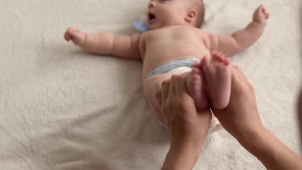 Cuidado de la piel de la salud, pediatría de desarrollo, primer plano del bebé las manos de la madre dan masaje del bebé recién nacido desnudo en brazos, piernas, dedos, reflejo en los pies ejercicio, frotando la piel abdomen pecho en la cama en casa — Vídeo de stock