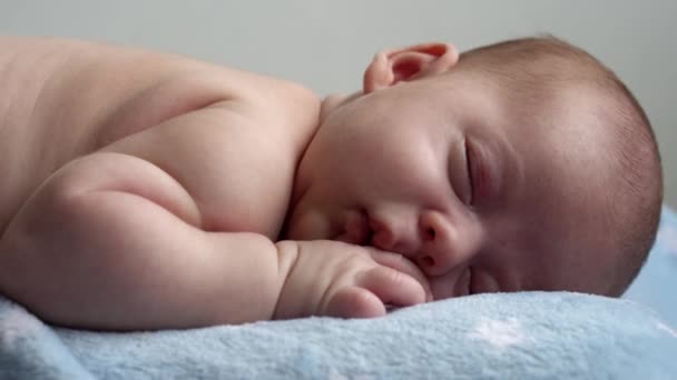 Infância, infância, desenvolvimento, medicina e saúde, amor, conceito de cuidado rosto close-up de recém-nascido nu dormindo pequeno bebê menino deitado no estômago no banquete azul macio na cama em casa — Vídeo de Stock