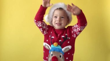Portre Duygusallığı Sevimli Mutlu Neşeli Chubby Bebek Yuvası Noel Baba Şapkası 'nda Gülümseyen ve Sarı Arkaplanda Kameraya Bakan Bebek. Çocuk Noel 'i kutluyor. Çocuk Yılbaşını Eğlenerek Geçiriyor