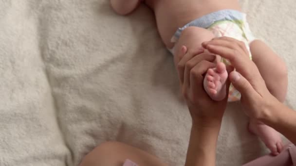 Gesundheitspflege, Entwicklungspädiatrie, Kleinkind Nahaufnahme Mutter Hände geben nackten Neugeborenen Baby Massage an Armen, Beinen, Fingern, Reflex auf den Füßen Übung, Reiben der Haut Bauch Brust auf dem Bett zu Hause — Stockvideo