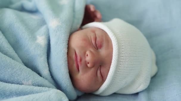 Retrato de la cara del bebé recién nacido Irritaciones alérgicas al acné Primeros días durmiendo sobre fondo azul. Niño al principio Minutos de la vida en sombrero. Bebés, Parto, Primeros Momentos Del Nacimiento, Principio Concepto — Vídeos de Stock