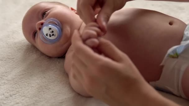Gesundheitspflege, Entwicklungspädiatrie, Kleinkind Nahaufnahme Mutter Hände geben nackten Neugeborenen Baby Massage an Armen, Beinen, Fingern, Reflex auf den Füßen Übung, Reiben der Haut Bauch Brust auf dem Bett zu Hause — Stockvideo
