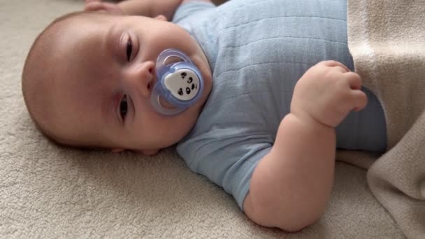 Gros plan mignon drôle enfant 2 mois nouveau-né garçon avec sucette regardant la caméra après la douche de bain sur lit doux blanc. Bébé enfant Temps de réveil avant le coucher. Enfance, maternité, famille, concept du nourrisson — Video