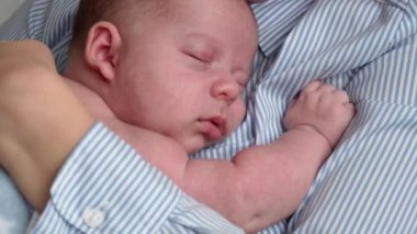 annelik, çocukluk, aile, bakım, sağlık, annelik konsepti - sıcak mavi battaniyeye sarılı yeni doğmuş bebek anne göğsünün kollarında uyuyor. Anne rahatla, kucağında öpücükle kucağında bebekle evde.