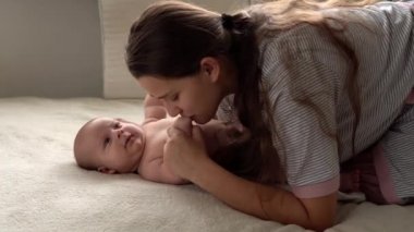 Otantik yakın çekim genç neo anne, doğum gününde beyaz yumuşak bir yatakta yeni doğmuş bebek bebekle oynuyor. Çocuk kavramı, ebeveynlik, çocukluk, hayat, annelik, annelik