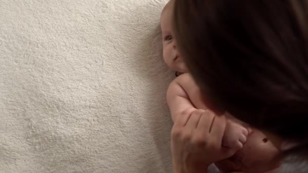 Autêntico close-up tiro jovem neo mãe mãe está brincando com nake bebê recém-nascido na cama macia branca no dia da manhã do berçário. Conceito de filhos, paternidade, infância, vida, maternidade, maternidade — Vídeo de Stock
