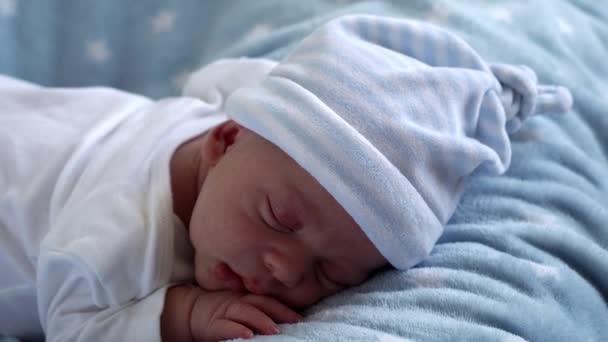 Nære på, nyfødte babyfjes-portrett, de første dagene hun sov søtt på Tummy Blue Star-bakgrunn. "Child at Start Minutes of Life on Hat" (engelsk). Spedbarn, fødsel, første borgmoment, begynnende begrep – stockvideo