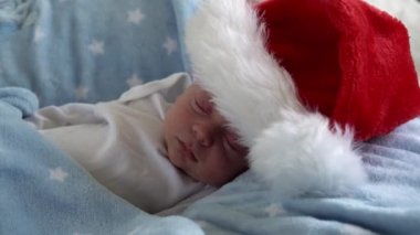 Hayatın ilk günleri yakın plan, yeni doğan tatlı, komik, Noel Baba 'nın içinde uyuyan bebek, kırmızı şapkalı, mavi yıldızlı arka planda yatıyor. Mutlu Noeller ve mutlu yıllar, bebekler, çocuklar, tatiller