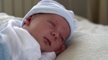 Yakın plan Yeni Doğmuş Bebek Yüzü İlk Günler Mavi Göbek Arkaplanında Tatlı Uyuyan Bebek Portresi. Hayata Başlayan Çocuk Şapka 'da. Bebekler, Doğum, Doğumun İlk Anları, Başlangıç Konsepti