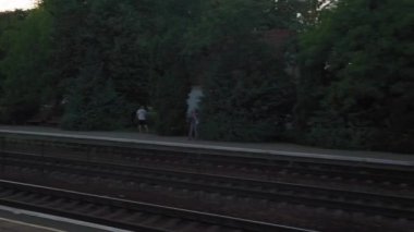 Terk edilmiş eski istasyon ve paslı yük vagonları üzerindeki yüksek hızlı trenden manzara. Tren rayları akşam gökyüzü günbatımında yaz arkaplanında. Ulaşım, seyahat, demiryolu, iletişim konsepti