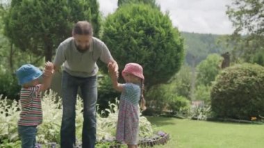 Sakallı ve Kardeşleri Kollarında İki Okul Öncesi Çocuğu Asılı Mutlu Aile Babası. Baba, Kız ve Oğul, Güneşli Yaz Günü 'nde Idyllic Banliyö Evinin arka bahçesinde eğlenceli oyunlar oynuyor.
