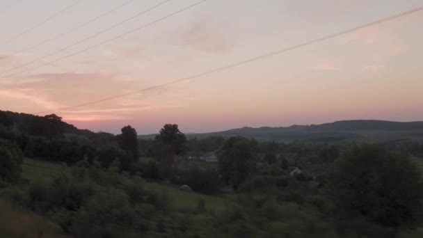 View from window high-speed train on landscape of nature field and forest on evening dusk sky sunset in summer background. red setting sun on horizon. Transport, travel, railway, communication concept — Stock Video