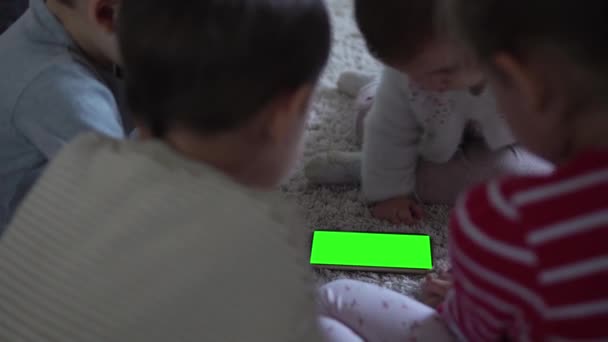 Adorable alegre suerte inteligente alegre niños pequeños en la alfombra usando Smartphone pantalla verde teléfono móvil Hromakey Ver vídeos Relajante en casa Dibujos animados Jugar juegos de Internet. Niños disfrutan aprendiendo — Vídeos de Stock