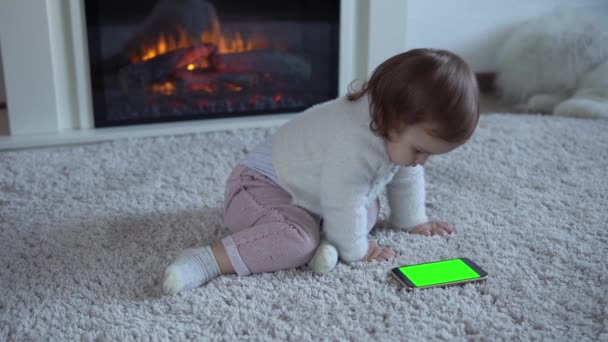 Adorável alegre sorte inteligente criança bebê menina no tapete fofo usando Smartphone tela verde celular Hromakey assistir vídeo Cartoon relaxar em casa Jogar jogos de Internet. Kid gosta de aprender — Vídeo de Stock