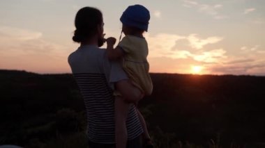 Parktaki insanlar. Sahada mutlu bir aile. Babam anaokulu kızıyla birlikte gün batımından önce uzun otların arasında dağın tepesinde. Aileler ve eğlenceli çocuklar mesafeye bakarlar. Yaz, babalık, çocukluk kavramı.