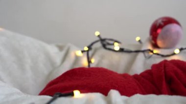 Yeni doğan bebeğin ilk yakın portresi. Beyaz çelenk arka planında kırmızı beze sarılı, Noel Baba şapkalı komik uyuyan bebek. Mutlu Noeller, Mutlu yıllar, Bebek, Çocukluk, Kış Konsepti