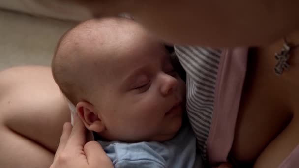 Macierzyństwo, dzieciństwo, rodzina, opieka, zdrowie, macierzyństwo - zbliżenie snu noworodka w niebieskim body śpiącego na ramieniu matki. Mama głaszcze twarz pocałunek przytulić trzymając niemowlę dziecko w łóżku w domu — Wideo stockowe