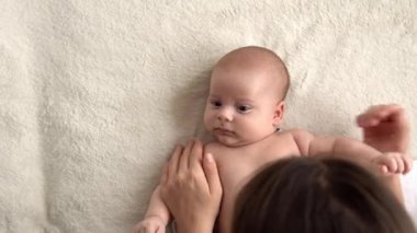 Otantik yakın çekim genç neo anne, doğum gününde beyaz yumuşak bir yatakta yeni doğmuş bebek bebekle oynuyor. Çocuk kavramı, ebeveynlik, çocukluk, hayat, annelik, annelik
