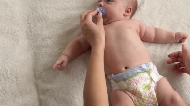 健康管理、発達小児科、乳児クローズアップの母親の手は、腕、足、指、足の運動に対する反射、自宅でベッドの上で皮膚腹部の胸をこすり、裸の新生児の赤ちゃんのマッサージを与えます — ストック動画