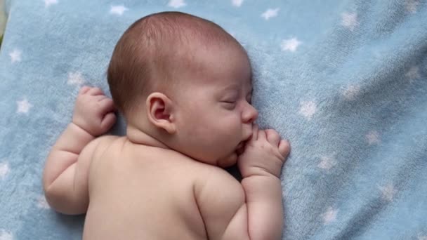Kojence, dětství, vývoj, zdraví, láska, péče koncept - pohled shora zblízka tvář novorozence nahé spaní relaxovat malý kojenec chlapec ležící na břiše na měkké modré banket na posteli doma — Stock video