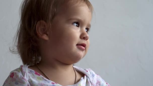 Schöne charmante lustig fröhlich lächelnd verspielt kleine energische nackte Kleinkind Kind. Baby Mädchen mit lockigen langen Haaren Kleider spielen zeigt verschiedene Emotionen weißen Hintergrund zu Hause auf dem Bett — Stockvideo