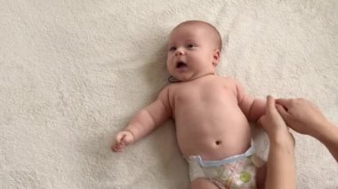 Cilt bakımı, gelişim pediyatrisi, bebek yakın çekim anne elleri kollara, bacaklara, parmaklara, ayak egzersizlerinde reflekslere, evde yatakta cilt göğsüne masaj yapar.